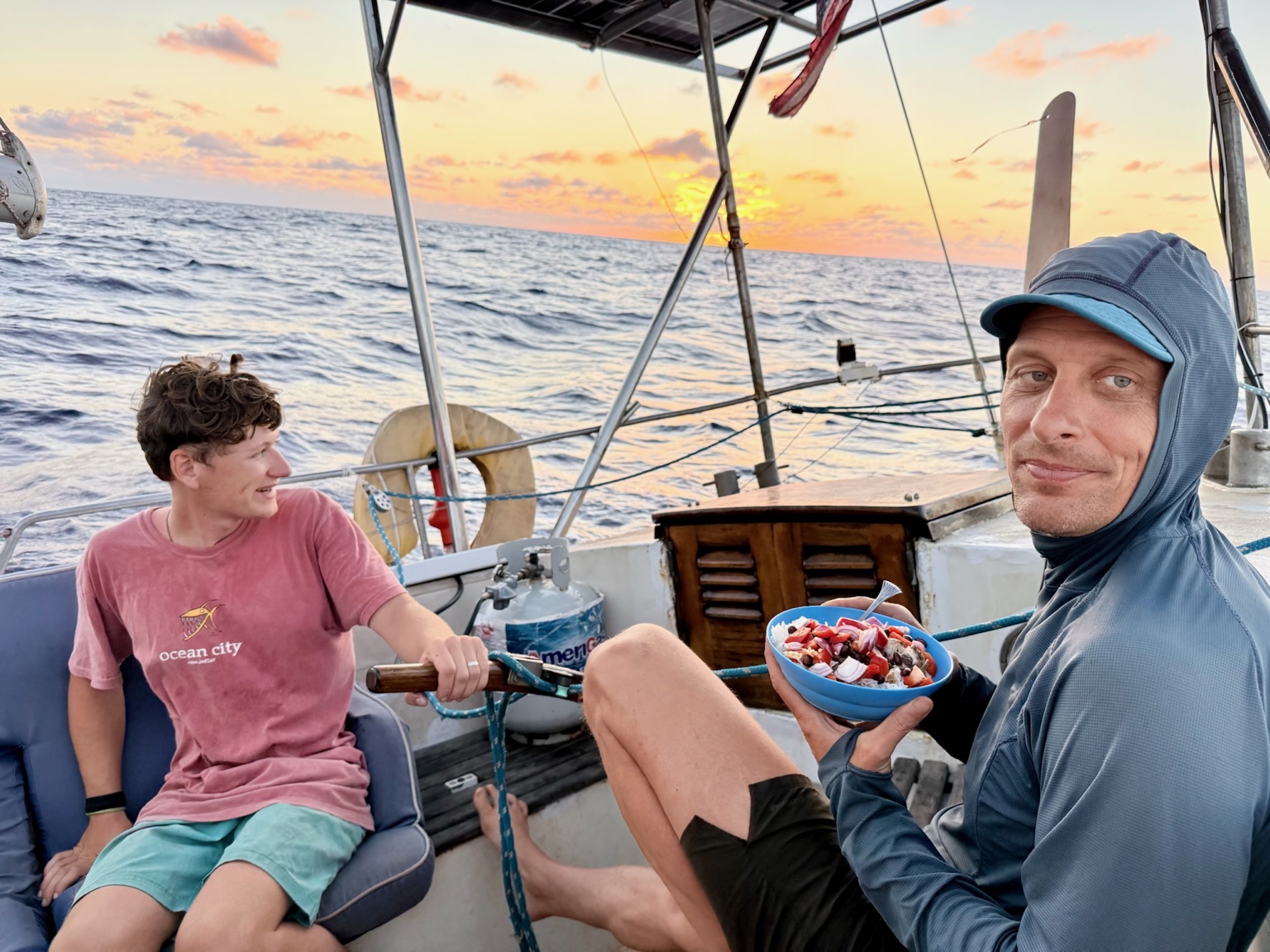 Two people enjoying food in the cockpit at sunset
